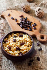 Sweet millet porridge with dark raisins in ceramic rustic bowl