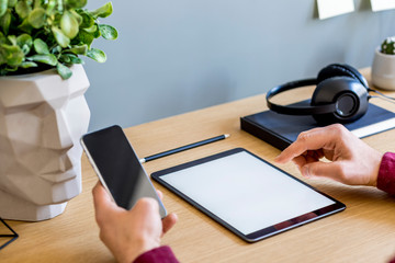Modern business composition on the home office with freelancer, mock up tablet screen, plant, notes, mobile phone and office supplies in stylish concept of home decor.