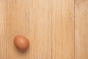  one chicken eggs on wooden background, top view and copy space for text