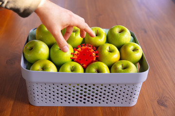 Coronavirus hiding in usual things - check cleanse and freshness of your fruits and food. Human hand's going to take apple, orange or lemon from the table. Pandemic, epidemic concept, disinfecting.