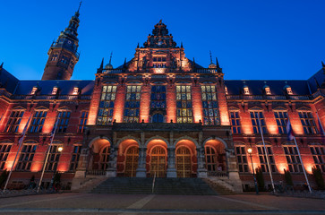 Historic building and empty square in the old town of Groningen illuminated at twilight.