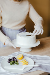 Housewife is cooking homemade lemon cake. Above view of human hands busy with pastry cooking using knife. Recipe of organic cake.