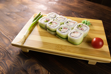 sushi rolls with cucumber, chicken, green leek and tomato on wooden board with wasabi