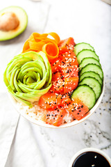 Salmon poke with avocado, cucumber, and rice on marble background , top view. Asian trendy food