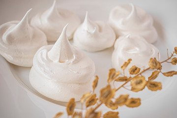 Homemade meringue on a white plate, decorated with dried flowers