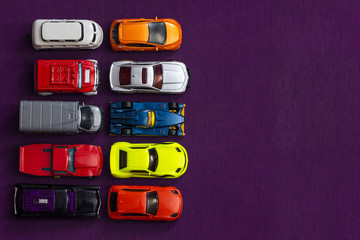 Colorful children's toy cars. Purple background. Bright colors. Automotive business concept. Empty place for text. Flat lay composition. Favorite children's toys.