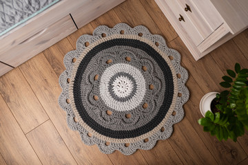 Handmade round yarn rug. Crafts from yarn. A gray carpet is lying by the bed.