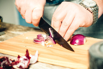hands cut onion on a kitchen board close-up