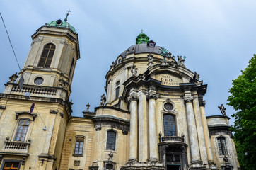 Fototapeta na wymiar Main facade of The Dominican church (Holy Eucharist) and monastery with huge bell tower and dome, tall columns t the entrance in Lviv, Ukraine is located in the city`s Old Town