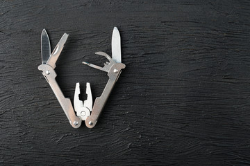 Multi-functional tool on a black textural background.