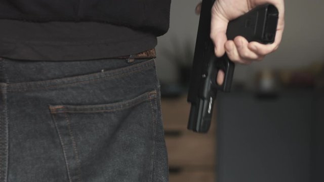 Anonymous man loading a nine millimeter toy gun perfect replica at home close up