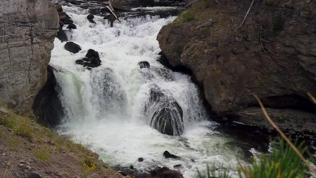 Slow motion shot of water coming down in the river from a water fall. Fire hose falls in Yellowstone.