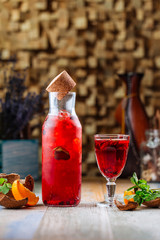 Side view on fresh cool orange berry lemonade with mint on the wooden table, vertical