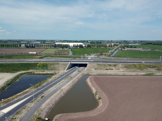 Fototapeta premium Drone photo of a traffic tunnel with motorways and green lawns around it on a beautiful cloudly skyn a beautiful cloudly sky 
