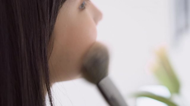 Beauty young asian woman happy and smile with face looking mirror applying makeup with brusher of cheek in the room, beautiful of girl holding brush make-up on facial, skin care and cosmetic concept.