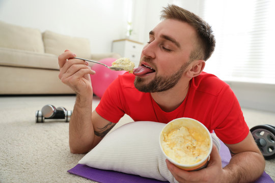 Lazy Young Man Eating Ice Cream Instead Of Training At Home