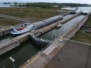 Naklejka na ściany i meble Photograph made with a drone of an Inland navigation vessel in the lock of near enkhuizen, this lock is a naviduct where the traffic passes under the concrete lock