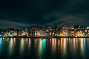 Night Amsterdam city view, Netherlands, traditional houses and Amstel river, Netherlands.