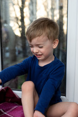 portrait of a crying little boy against the window