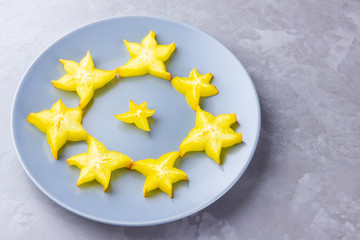 Carambola on a gray plate. Sliced fresh carambola on a gray background. Slices of star fruit....