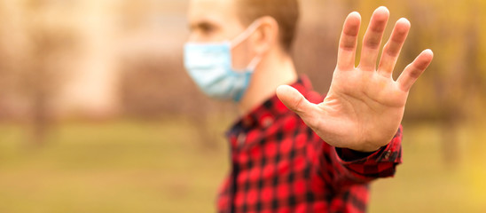 Banner view of man with medical face mask showing stop gesture outdoor. People, healthcare and...