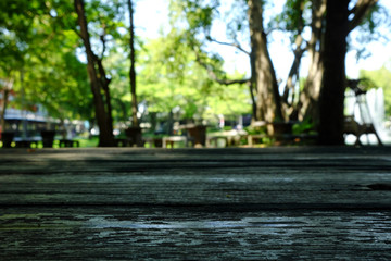 Old Wood Table with Nature Bokeh in Public Garden Background, Suitable for Background, Backdrop, and Mock up.