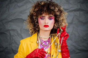 Portrait of a girl in a yellow jacket and blue jeans with afro hair of the eighties, disco era....