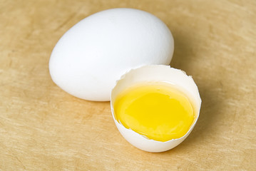 chicken white eggs with half broken egg on beige textured background