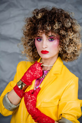 Portrait of a girl in a yellow jacket and blue jeans with afro hair of the eighties, disco era....