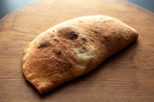 Broccoli rabe, olive and&dagger;parmesan&dagger;calzone on wood