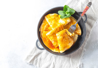 Crepes with Orange Sauce in a cast iron pan. Traditional French crepe Suzette with orange sauce.