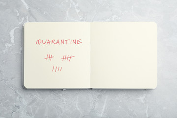Open notebook on marble table, top view. Counting days of quarantine during coronavirus outbreak