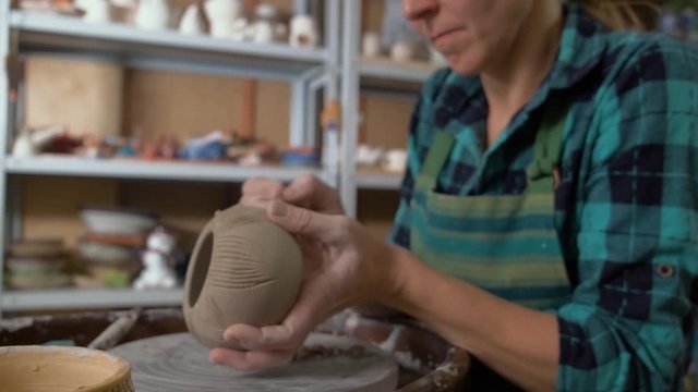 Girl Potter creates a vase. The formation of the pattern on the clay vase. Panorama from the hands to the face