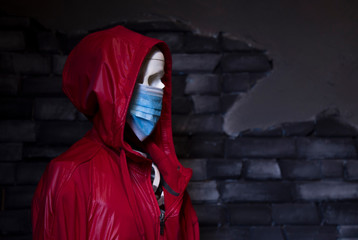 Human skeleton in a medical mask and a red cloak with a hood. Coronavirus pandemic concept with...