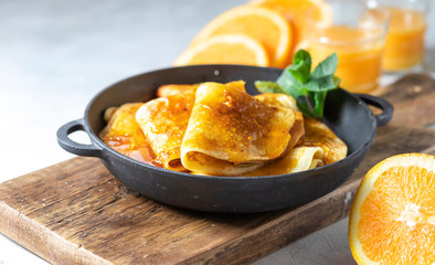 Crepes with Orange Sauce in a cast iron pan. Traditional French crepe Suzette with orange sauce.