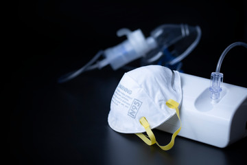 N95 mask with Nebulizer medical device for inhalation treatment on dark surface. 