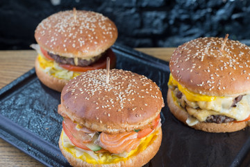 A close-up photograph of the mouth-watering author's bergers, with a variety of flavors, including shiemgo, cheese, and beef meatballs. In a rustic style, on a dark background of a stone wall