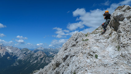Fototapeta na wymiar Tourist takes a picture of beautiful views from the mountain trail in the Dolomites