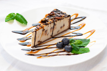 Sweet cheesecake on a white plate with blueberries and mint leaves