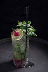 close-up, advertising shot of a light alcoholic cocktail, with a sprig of mint, icing sugar, with decorative grape berry. In a rustic style, on a dark background.