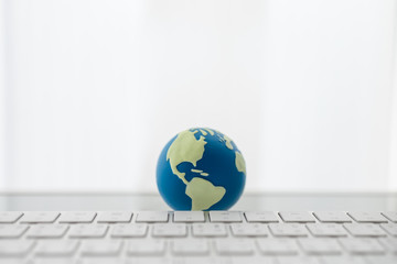 Global Business and Technology Concept. Close up of mini world ball with computer keyboard with copy space.