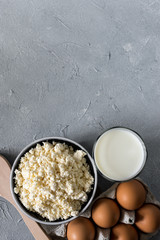 healthy food concept, homemade cottage cheese, a glass of milk, yogurt and chicken eggs on a stone background, dairy products