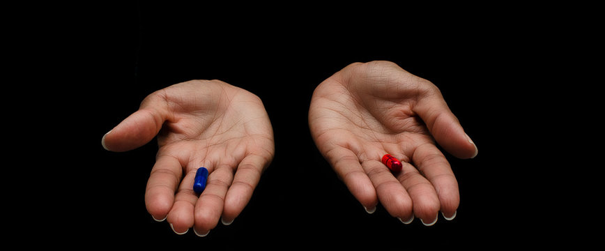 Hands of a black woman offering the red and the blue pills on a black background.  Concept of ugly truth vs beautiful lie, reality vs fiction.