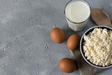 healthy food concept, homemade cottage cheese, a glass of milk, yogurt and chicken eggs on a stone background, dairy products