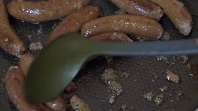 Grill Tongs flipping Sausages on a sizzling hot grill plate