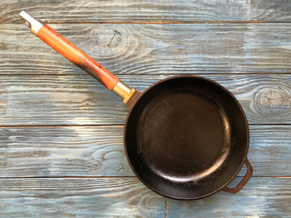 cast iron pan with wooden handle on a wooden blue table
