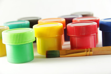 Close-up of colorful gouache paint for painting in cans with a brush on a white background. Objects...