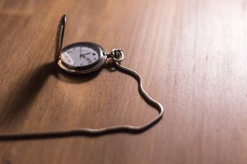 Reloj de bolsillo antiguo de plata sobre fondo de madera.