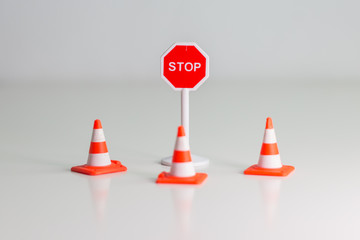 Señal de tráfico de STOP rodeada de conos de señalización sobre fondo blanco.