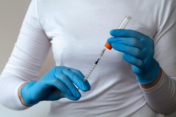 Medical healthcare. Doctor hands in blue gloves holds and prepares a vaccine in an injection syringe. nurse with syringe at home. gloved hand holding a syringe. People in white uniform in lab.